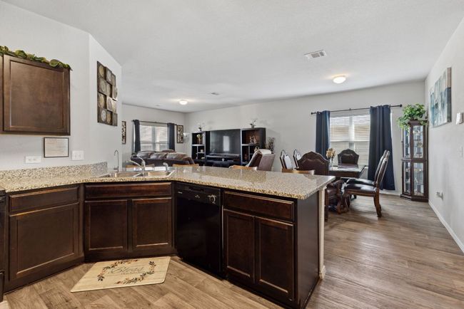 Kitchen featuring black dishwasher, a sink, open floor plan, a peninsula, and dark brown cabinets | Image 24