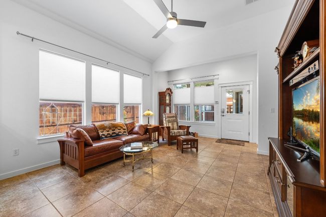 Living room with a wealth of natural light, light tile patterned floors, baseboards, and ceiling fan | Image 13
