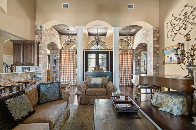 Living area featuring hardwood floors, a high ceiling, and ornate columns. | Image 8