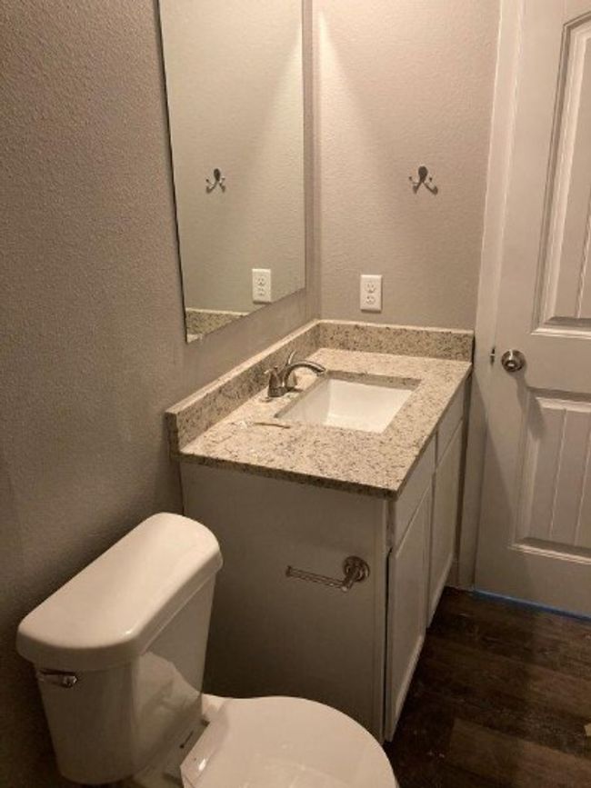 Half bathroom featuring toilet, vanity, wood finished floors, and a textured wall | Image 6