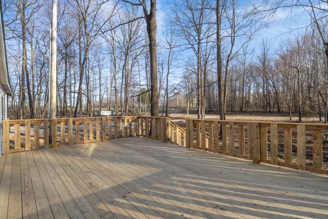 The spacious front deck offers a peaceful wooded view and sits well back from the street for added privacy. It’s the perfect spot for grilling with friends, enjoying morning coffee, or unwinding in the evening surrounded by nature. | Image 17