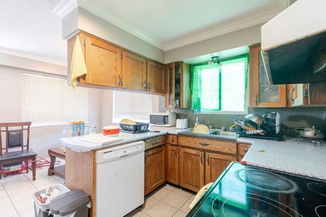 Kitchen with white appliances, light tile patterned floors, light countertops, decorative backsplash, and a peninsula | Image 5