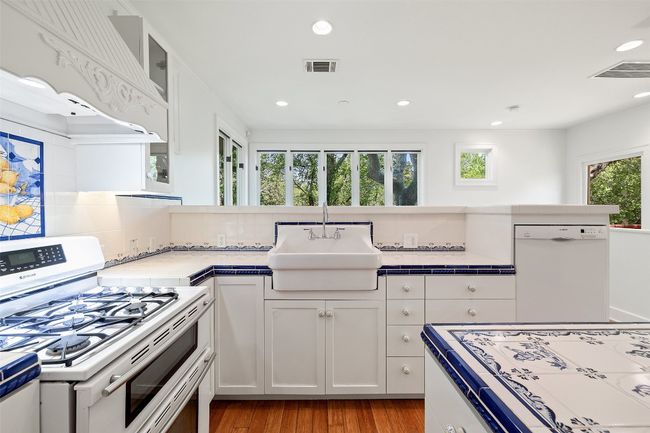 Kitchen featuring white cabinetry, gas range, visible vents, white dishwasher, and a sink | Image 10