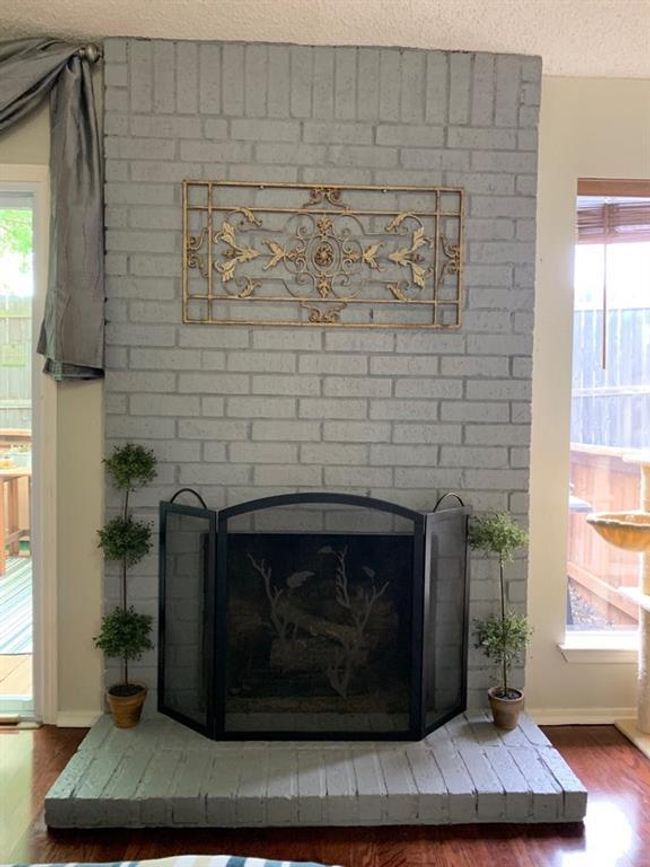 Detailed view of wood finished floors, a brick fireplace, baseboards, and a textured ceiling | Image 4