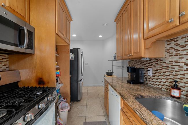 Kitchen with stainless steel appliances, backsplash, stone countertops, a sink, and light tile patterned flooring | Image 14