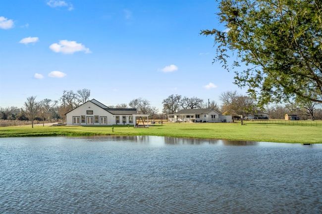 Another view across the pond—framing the property’s two living spaces and wide-open land beyond. | Image 38