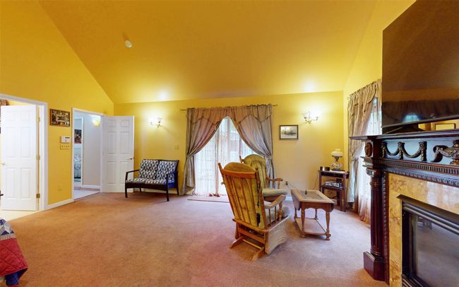 Carpeted living area featuring high vaulted ceiling, a fireplace, and baseboards | Image 42