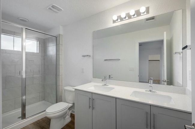 Bathroom with double vanity, a shower stall, and wood finished floors | Image 5