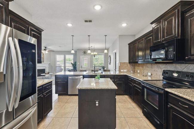 Kitchen with visible vents, a sink, a ceiling fan, a peninsula, and black appliances | Image 6