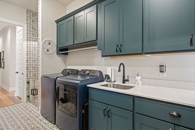 Laundry area featuring cabinet space, a textured wall, wood finished floors. | Image 34