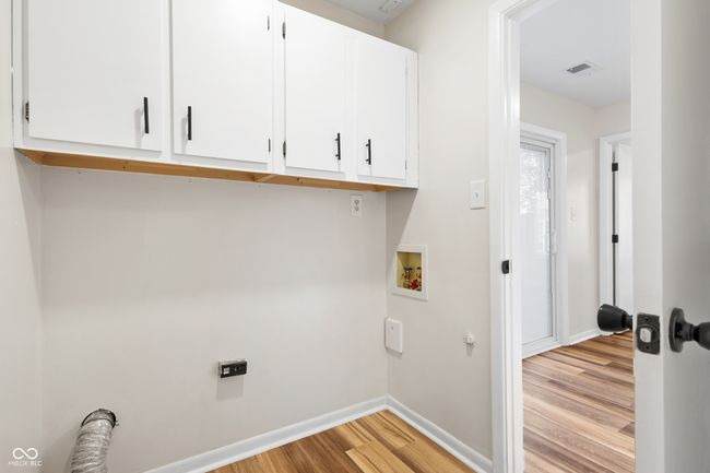 laundry room with electric dryer hookup, visible vents, hookup for a washing machine, light wood-type flooring, and cabinet space | Image 11