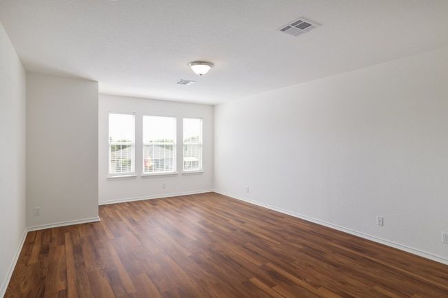 Empty room with dark wood-style flooring, visible vents, and baseboards | Image 21