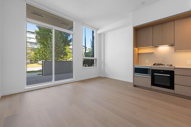 Kitchen with black oven, stainless steel microwave, plenty of natural light, and under cabinet range hood | Image 8