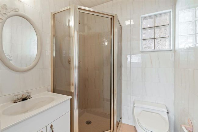 Bathroom featuring tile walls, an enclosed shower, vanity, and toilet | Image 11