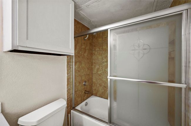 Bathroom featuring shower / bath combination with glass door and toilet | Image 12