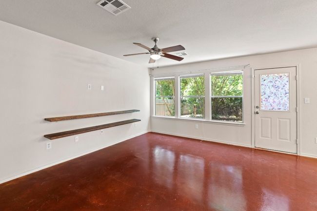 The living room includes a ceiling fan and several windows that help illuminate the space. | Image 6