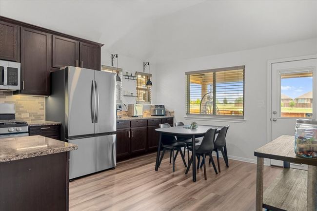 Kitchen with dark brown cabinetry, a wealth of natural light, light wood-style floors, and appliances with stainless steel finishes | Image 13