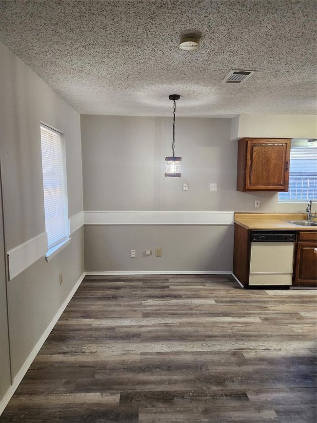 Kitchen featuring white dishwasher, a sink, a textured ceiling, dark wood finished floors, and light countertops | Image 7