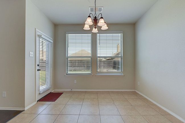 Unfurnished dining area with a chandelier, healthy amount of natural light, light tile patterned flooring, and baseboards | Image 7