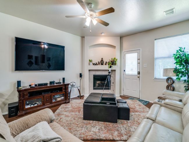 Living area featuring ceiling fan, baseboards, visible vents, and a tiled fireplace | Image 7
