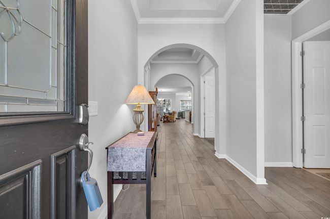 Entryway featuring baseboards, arched walkways, wood finished floors, and crown molding | Image 4