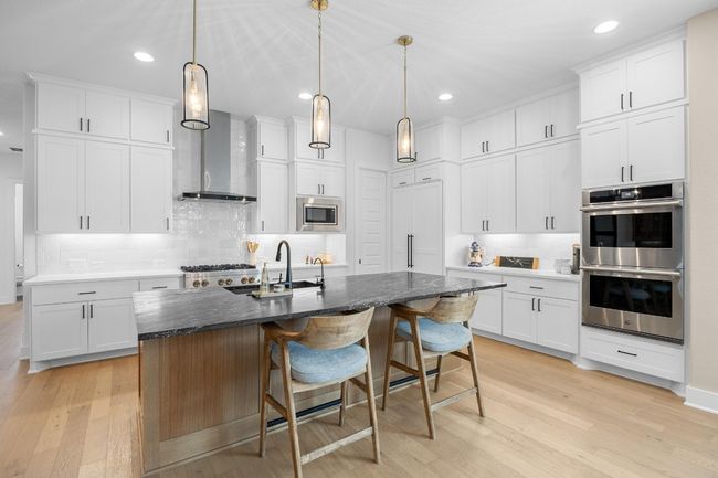 Kitchen with tasteful backsplash, light wood-style floors, appliances with stainless steel finishes, recessed lighting, and an island with sink | Image 7