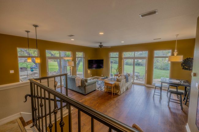 Large den featuring recessed lighting, hardwood flooring, full bar, game area, sitting area and large windows into back yard | Image 21