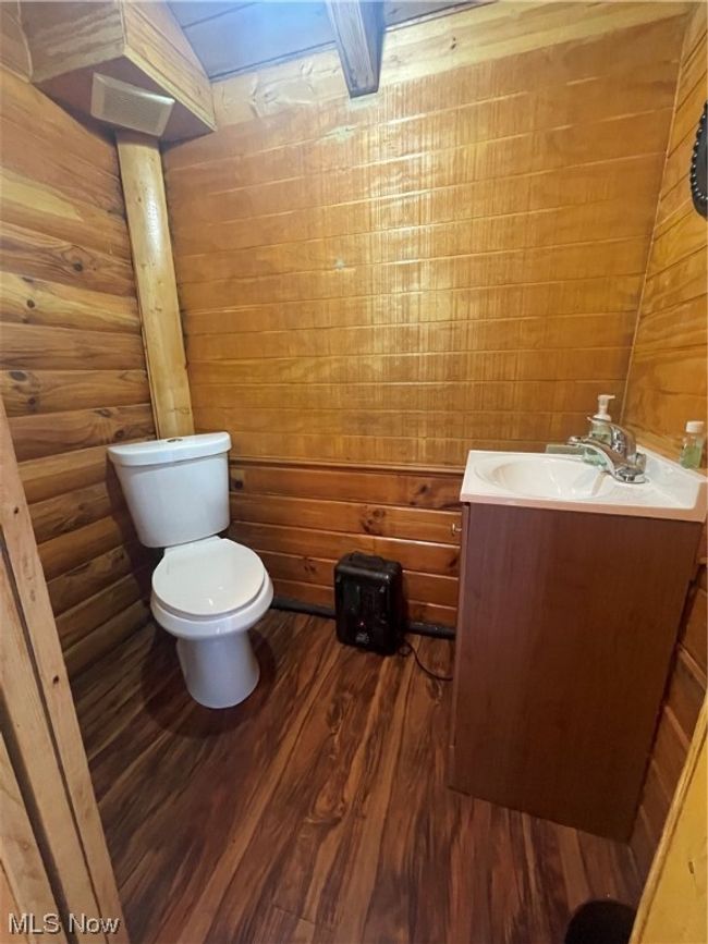 Bathroom featuring vanity, toilet, wooden walls, and wood-type flooring | Image 32