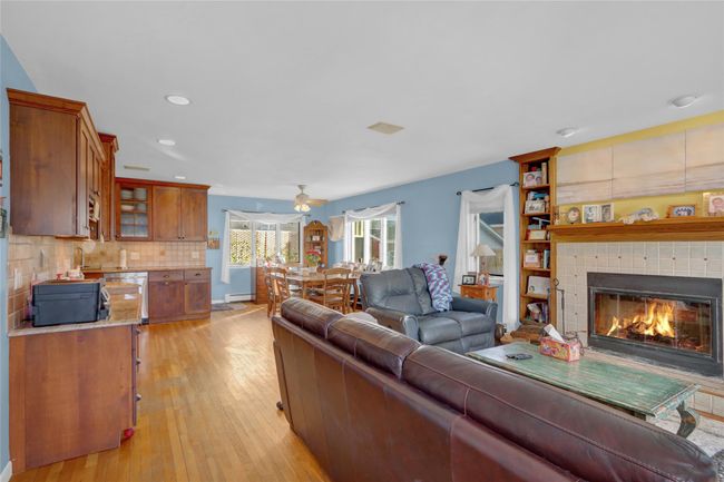 Living room featuring ceiling fan, light hardwood / wood-style flooring, a tile fireplace, and a baseboard radiator | Image 10