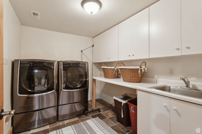 Washroom featuring cabinet space, washer and clothes dryer, and dark stone finish flooring | Image 45