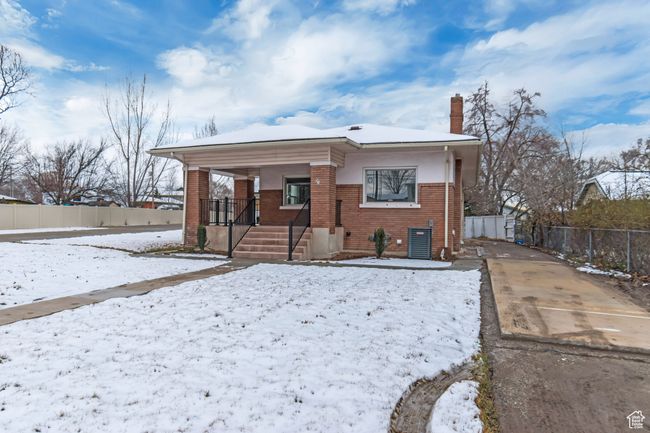 View of front facade with fence, covered porch, brick siding, and a chimney | Image 25