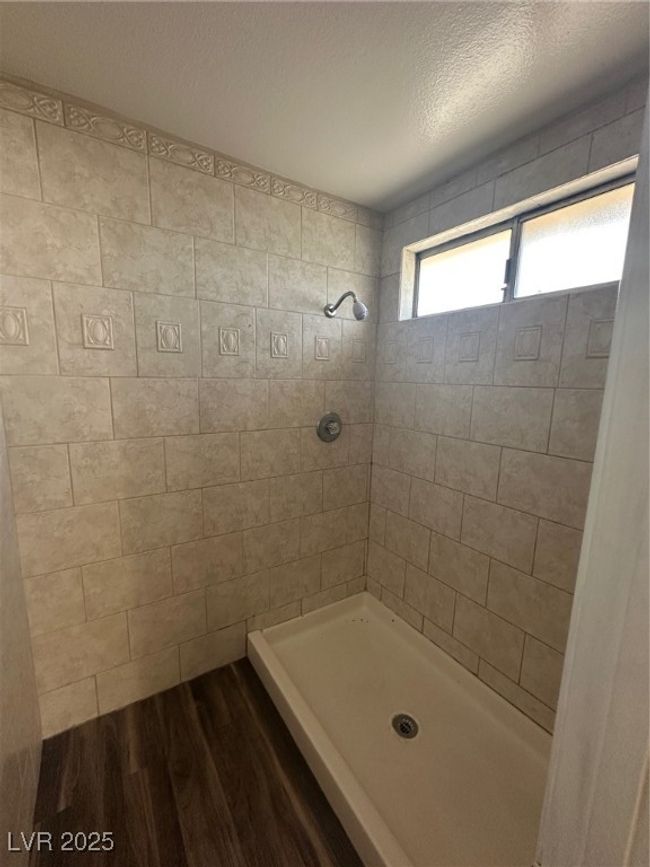 Bathroom featuring tiled shower, a textured ceiling, and wood finished floors | Image 18