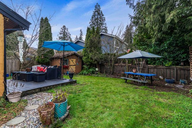 View of yard featuring an outdoor living space, a deck, an outdoor structure, and a fenced backyard | Image 8
