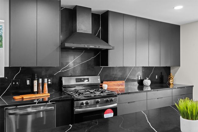 Kitchen featuring stainless steel appliances, wall chimney exhaust hood, modern cabinets, decorative backsplash, and recessed lighting | Image 8