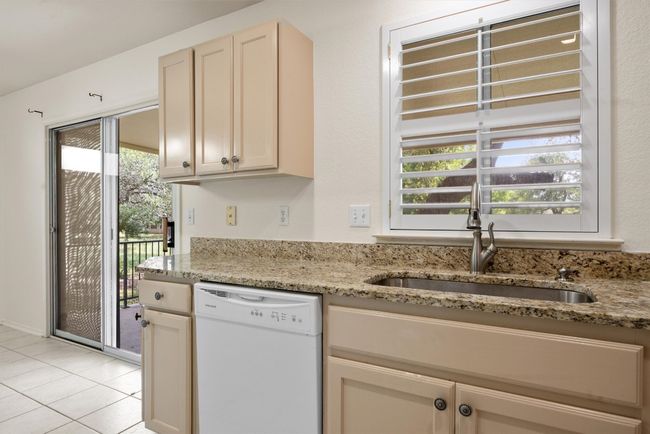Kitchen with white dishwasher, light stone countertops, and light tile patterned flooring | Image 22