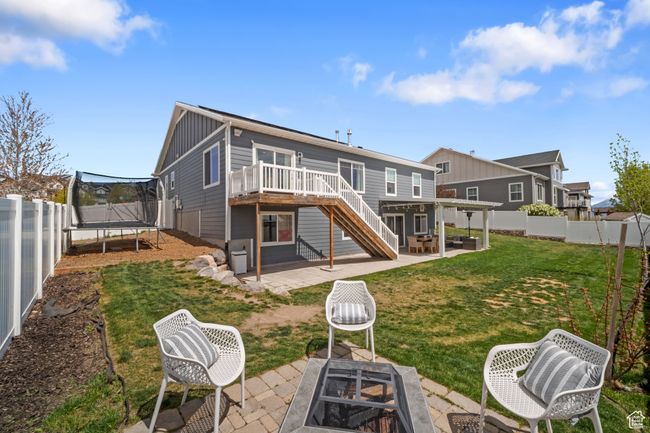Back of house with stairs, a wooden deck, a trampoline, a patio area, and an outdoor fire pit | Image 20