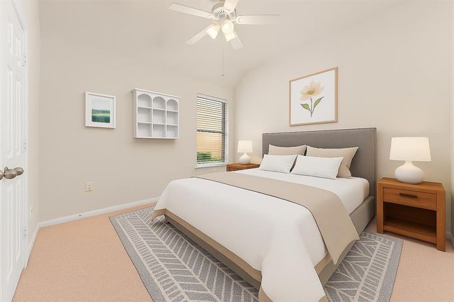 This light-filled secondary bedroom features a vaulted ceiling, neutral tones, and a large window overlooking the side yard. A ceiling fan and generous wall space make it a comfortable and versatile retreat for guests, children, or a home office. virtually staged | Image 30