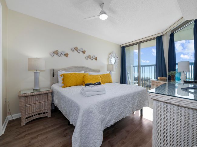 Bedroom featuring access to exterior, a textured ceiling, wood finished floors, a wall of windows, and ceiling fan | Image 22