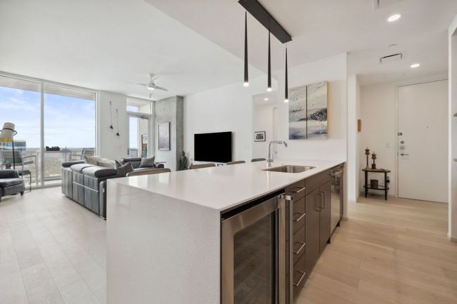 Kitchen featuring beverage cooler, a sink, a wall of windows, light countertops, and open floor plan | Image 8