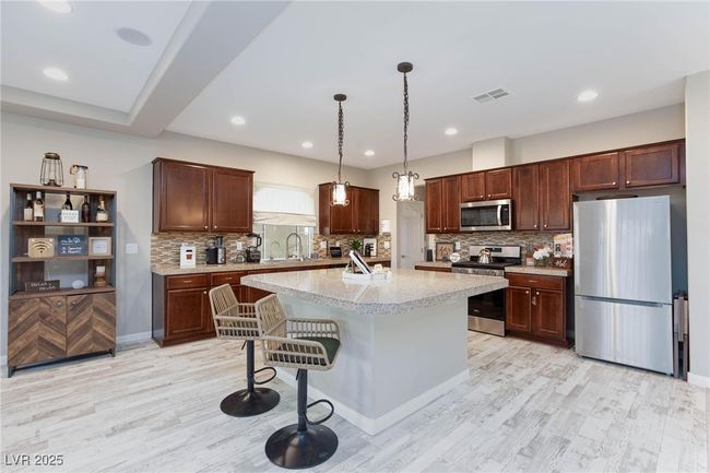 Kitchen with light wood-style flooring, a sink, visible vents, decorative backsplash, and appliances with stainless steel finishes | Image 13