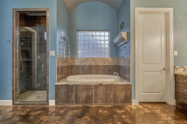 The soaking tub in the primary bath is beautifully accented with glass tile, which is echoed in the shower design for a cohesive, upscale look. A heated towel bar above the tub adds a luxurious touch, keeping towels warm and cozy. | Image 32