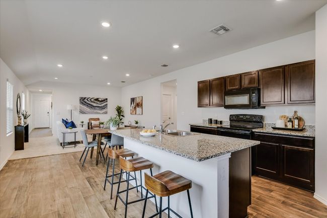 Kitchen featuring a sink, a breakfast bar area, recessed lighting, visible vents, and black appliances | Image 9