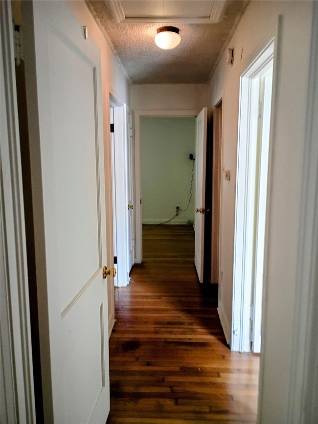 Hallway with dark wood-style floors, a textured ceiling, attic access, and baseboards | Image 9