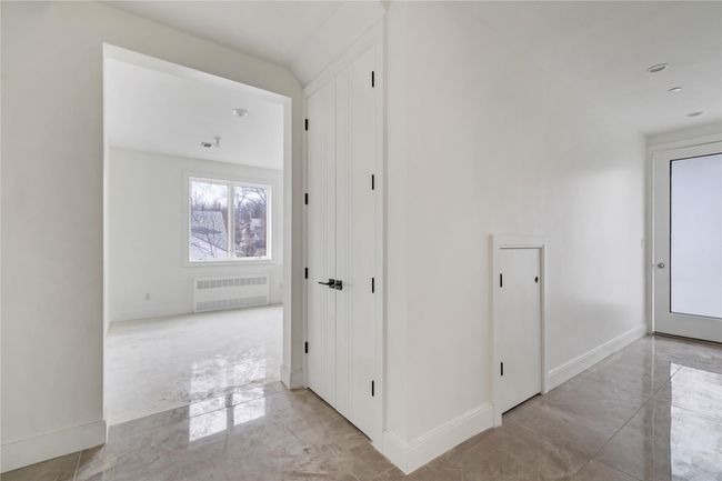 Hallway with marble finish floor, baseboards, and radiator heating unit | Image 6