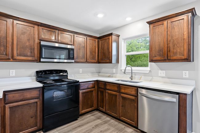 Kitchen featuring appliances with stainless steel finishes, light wood-style floors, light countertops, and recessed lighting | Image 9