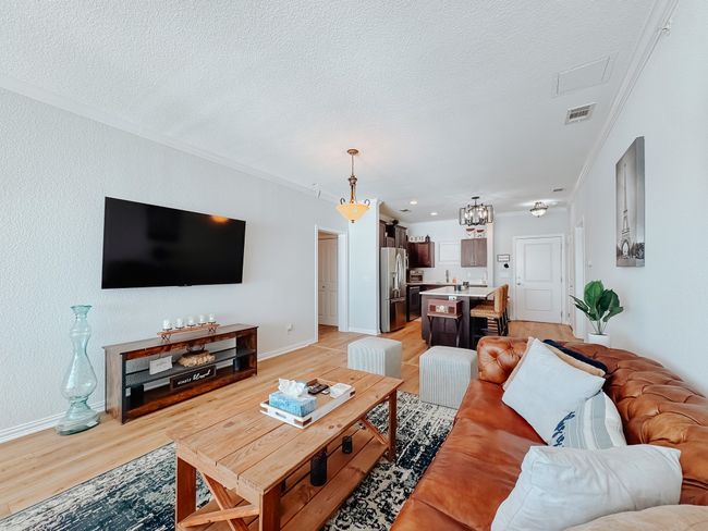Living area featuring baseboards, visible vents, light wood-style flooring, crown molding, and a textured ceiling | Image 14