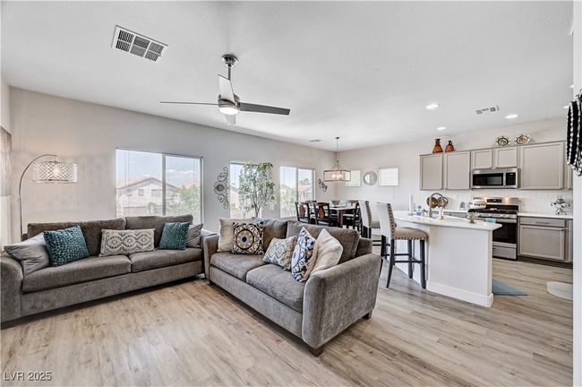 Living area featuring light wood-style flooring, ceiling fan, a chandelier, and recessed lighting | Image 11