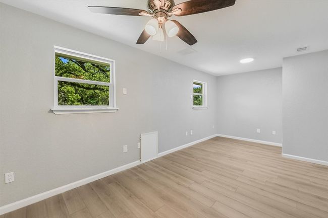 Spare room featuring light wood finished floors, visible vents, baseboards, and ceiling fan | Image 17