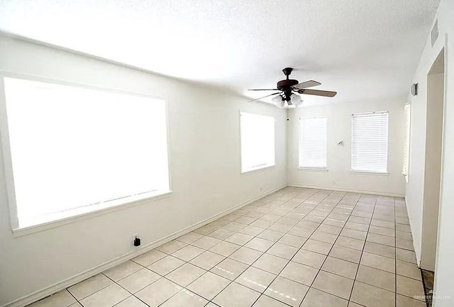Empty room with ceiling fan, light tile patterned flooring, and a textured ceiling | Image 7
