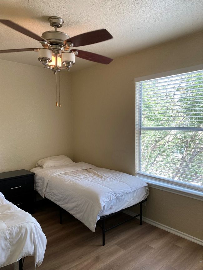 Bedroom with wood finished floors, baseboards, a ceiling fan, and a textured ceiling | Image 5